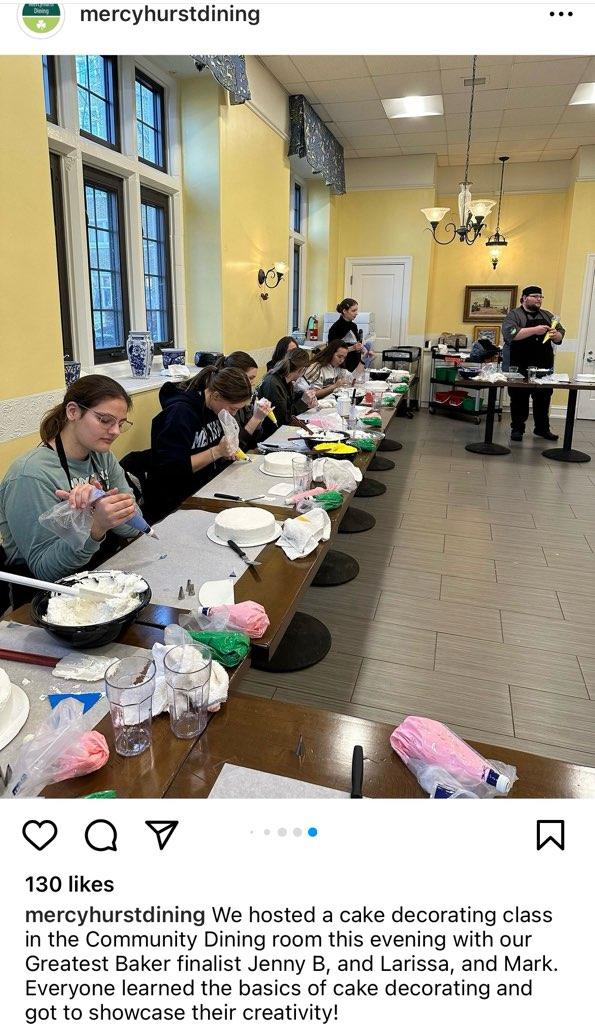 students sit in a row of tables practicing their cake decorating skills