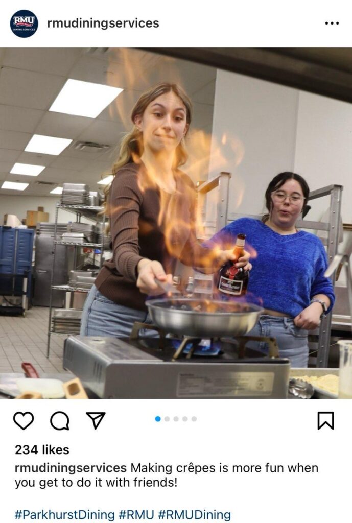 a student flips a crepe on a skillet over a flame