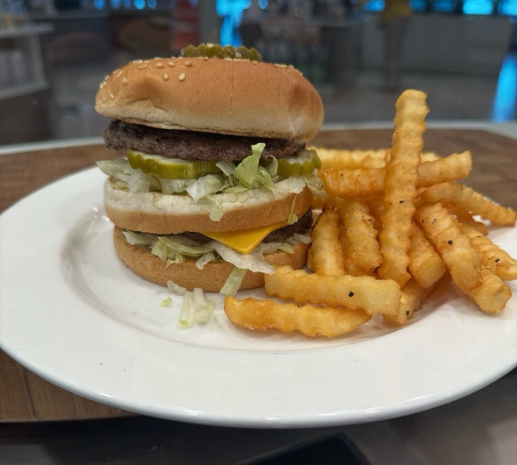 a double-decker burger with a side of crinkle-cut French fries