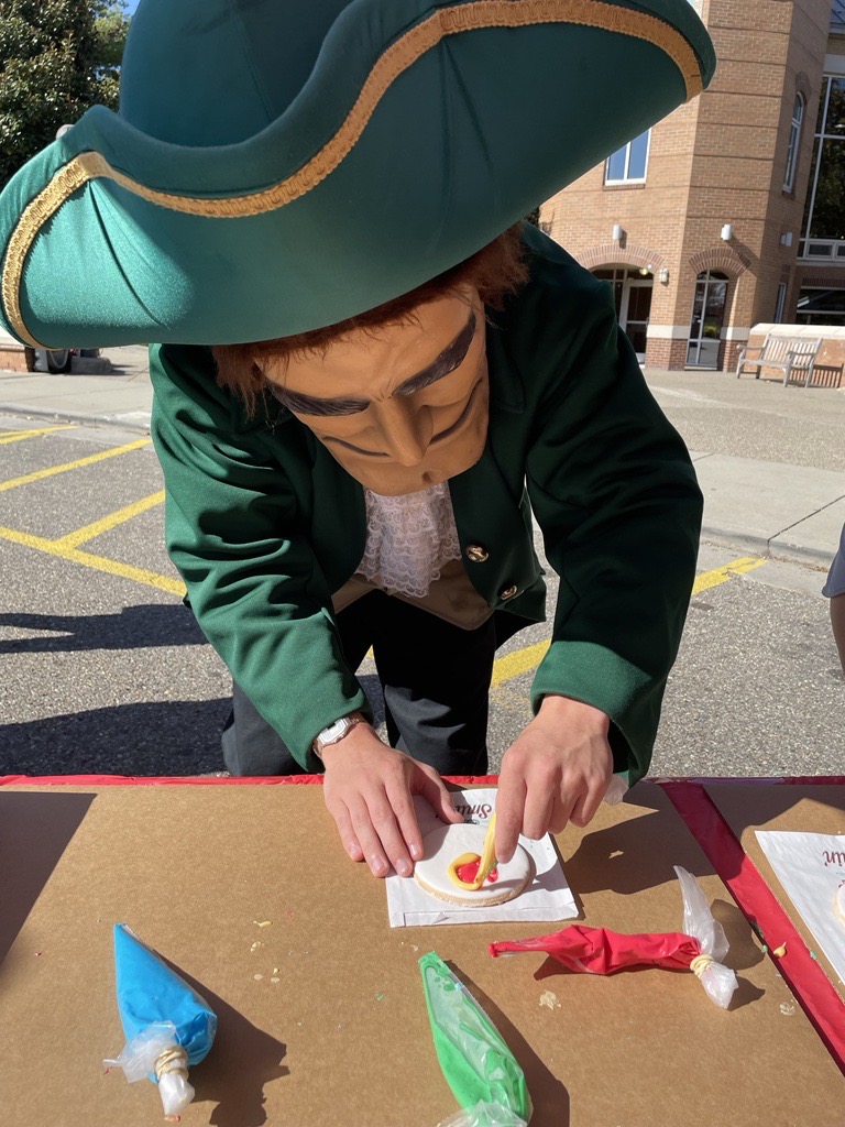 a mascot in a green hat and face mask decorates a cookie