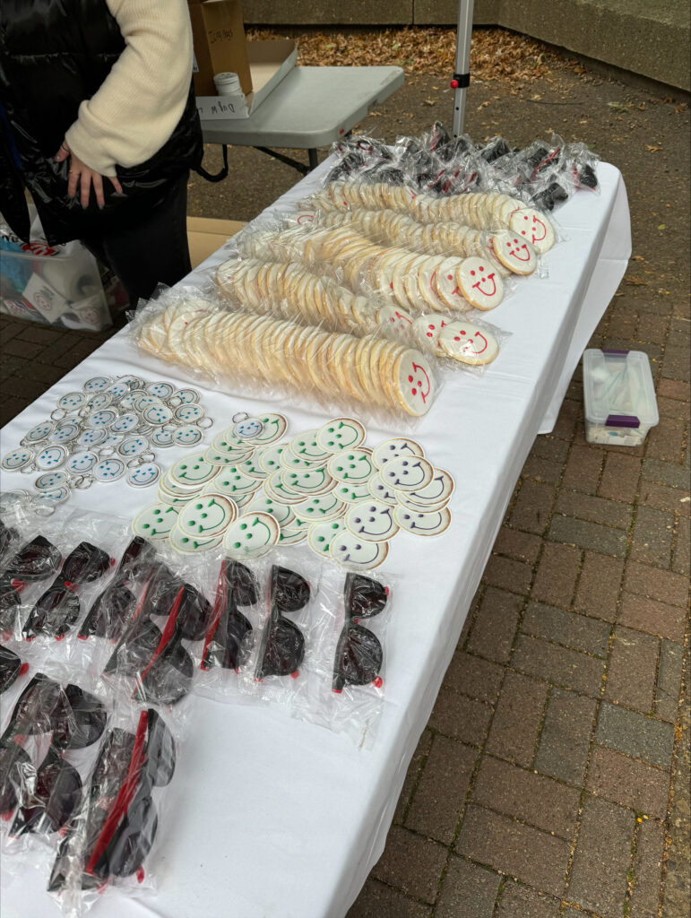 a table filled with Smiley Cookie swag, including sunglasses, stickers, and cookies