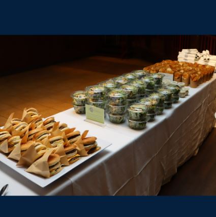 a table filled with burgers, salads, and napkins and silverware