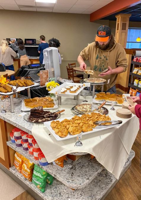 a table of cookies, cakes, and desserts with a man partaking in them
