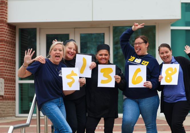 a group of team members hold up numbers denoting a total