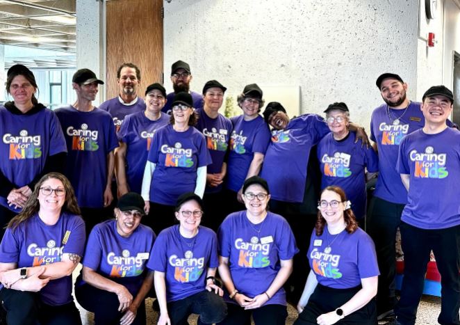 a group of dining team members in purple Caring for Kids shirts