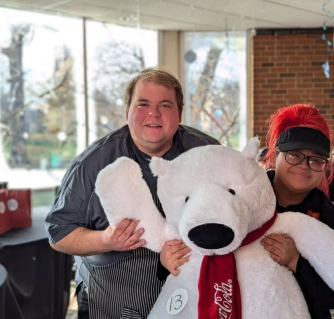 a man and a woman holding a white Coca Cola stuffed animal bear