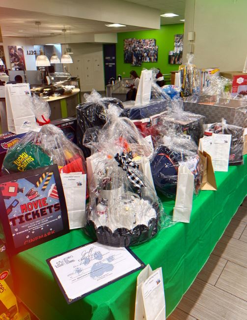 a table with a green table cloth filled with gift baskets wrapped in cellophane