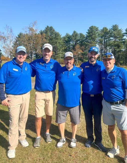 a group of men in blue shirts on a golf course