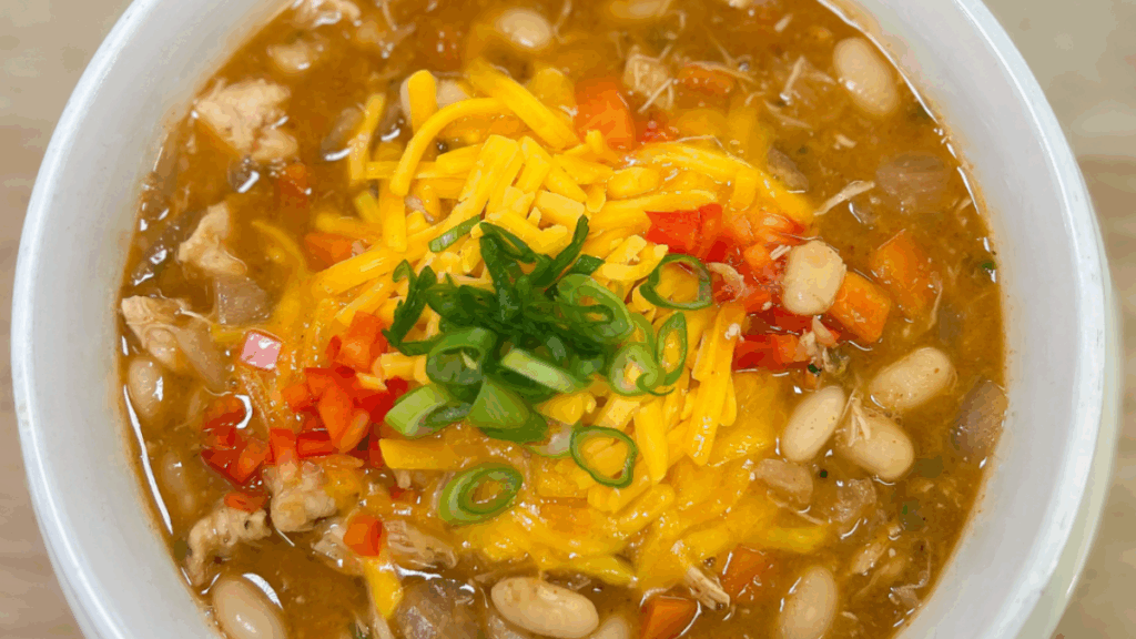 chicken chili from the top down, topped with green onions, cheddar cheese, and tomatoes