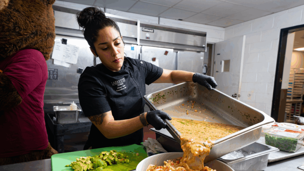 a female chef pouring a broth on a dish in the kitchen