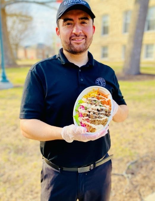 a Bibibop Asian Grill employee holds a fresh bowl with rice, meat, and veggies