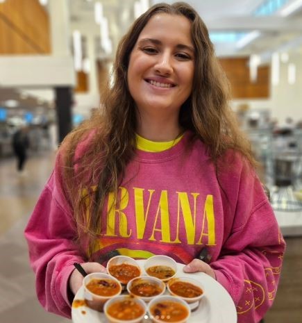 a girl wearing a nirvana shirt holding cups of chili