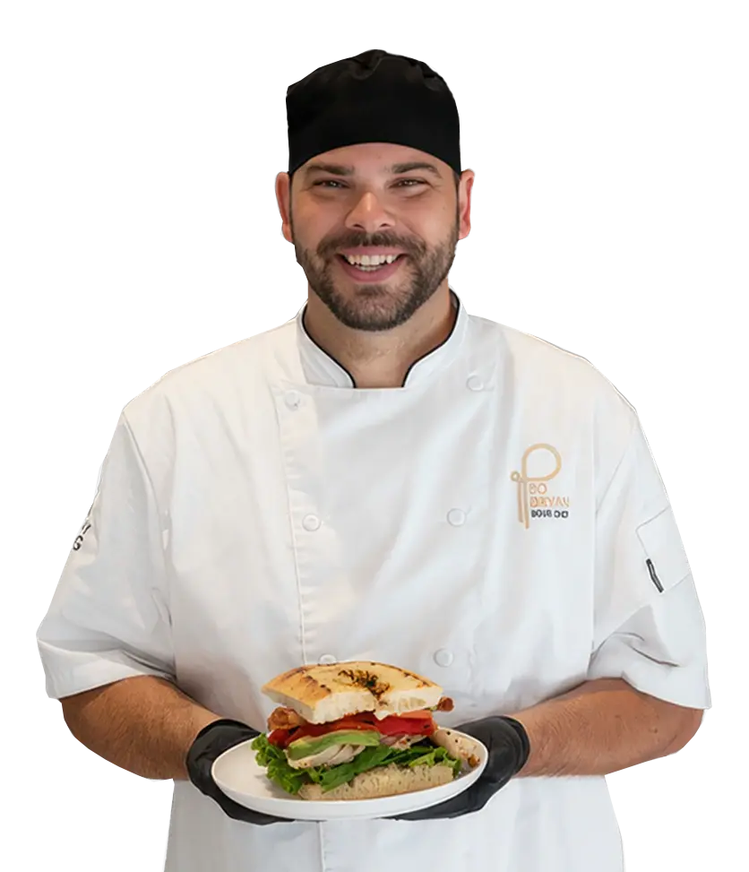 A Parkhurst chef stands proudly displaying a prepared sandwich.