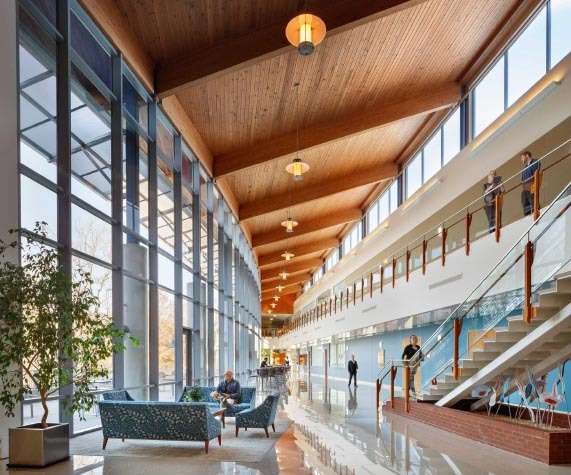 A window filled corporate workplace with a few people walking, is an example of where Parkhurst can showcase their innovation in dining.