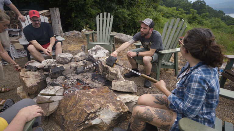 chefs sit around a campfire at a camp'n cook event