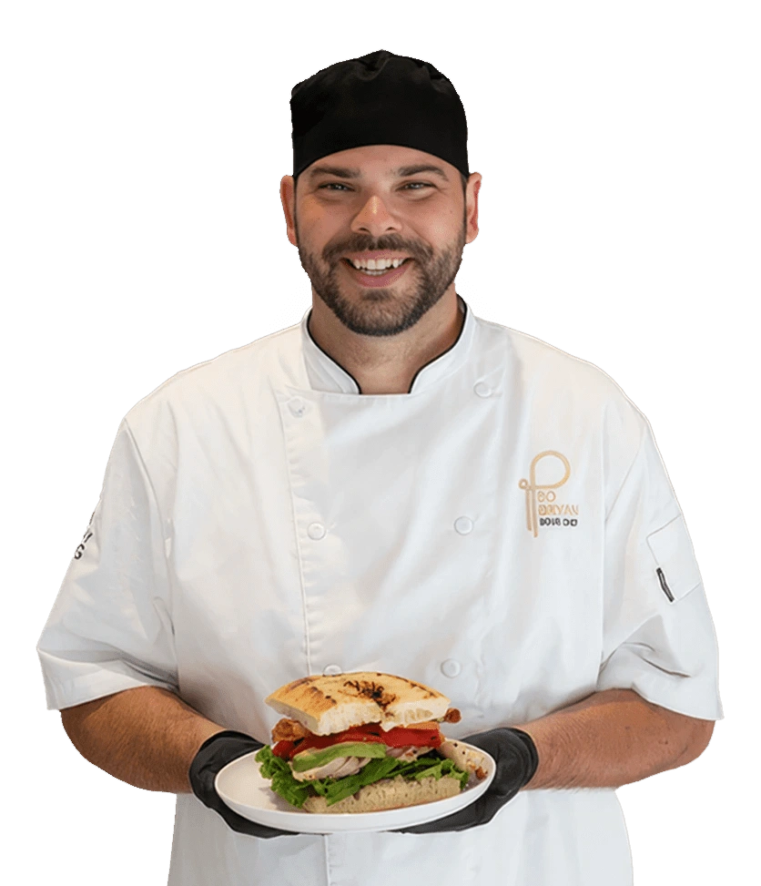 A Parkhurst chef stands proudly displaying a prepared sandwich.