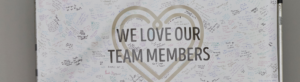 banner that says "we love our team members" with many signatures and notes from guests sharing their gratitude