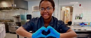 Parkhurst team member with heart hands over rainbow cupcakes for Pride Month