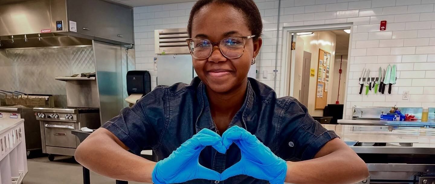 Parkhurst team member with heart hands over rainbow cupcakes for Pride Month