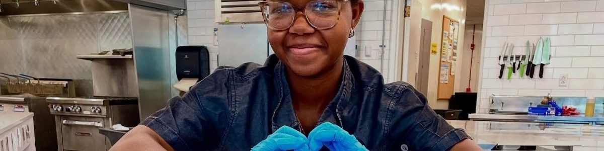 Parkhurst team member with heart hands over rainbow cupcakes for Pride Month