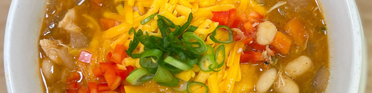 chicken chili from the top down, topped with green onions, cheddar cheese, and tomatoes