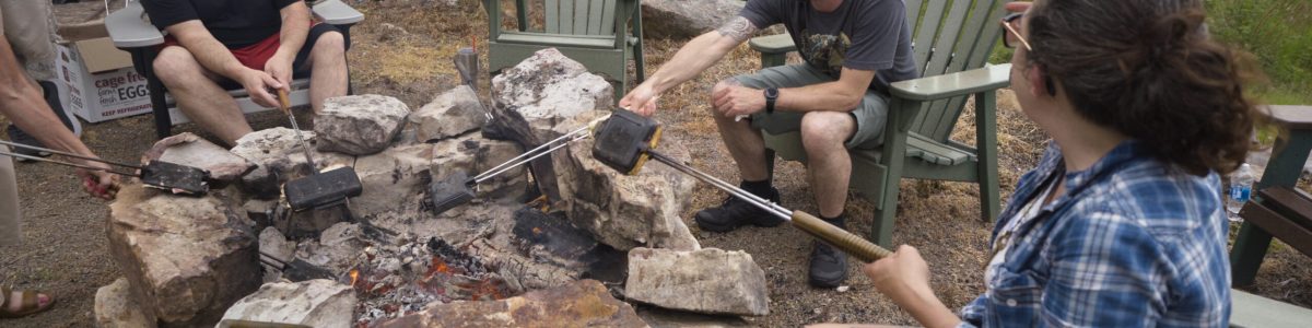 chefs sit around a campfire at a camp'n cook event