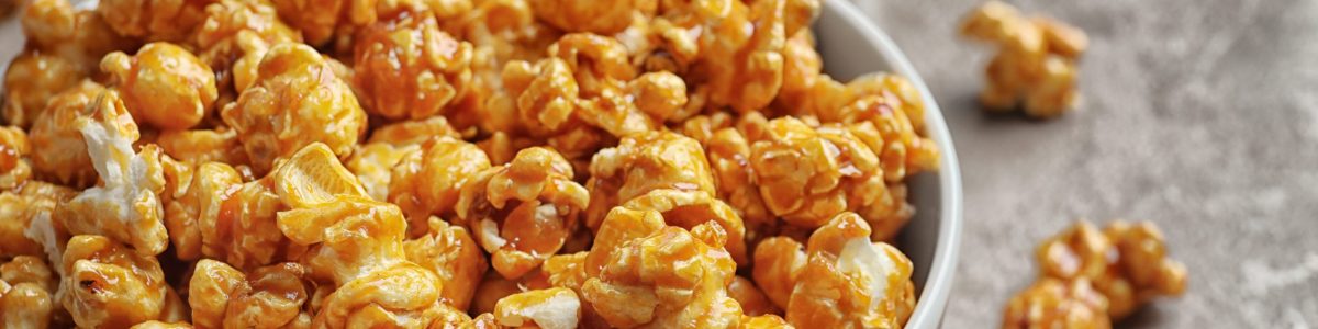 Delicious popcorn with caramel in bowl on table, closeup